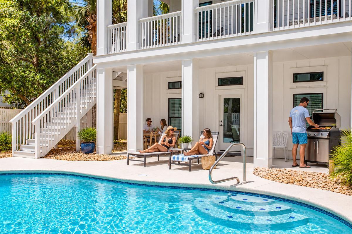 Blessed House 30A vacation home with private pool and family relaxing by the outdoor grilling area in Santa Rosa Beach.